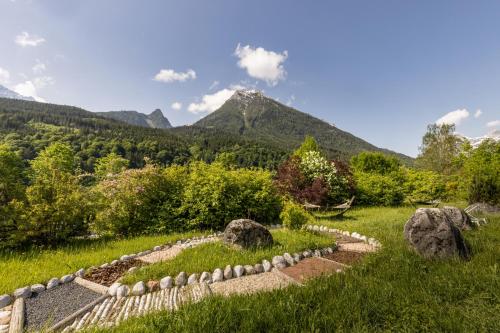 a garden with rocks and mountains in the background at Berghotel Rehlegg in Ramsau