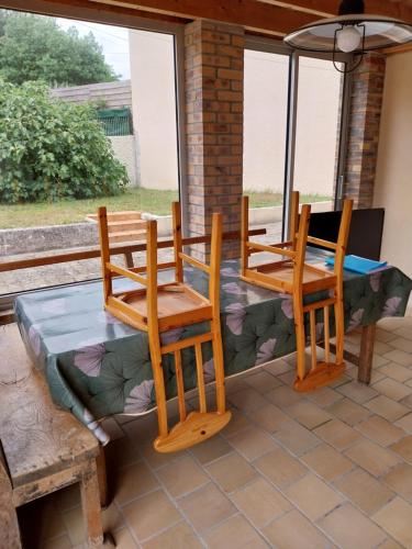 - 2 chaises en bois et une table sur la terrasse dans l'établissement Maison proche de la Mer, à Barneville-Carteret