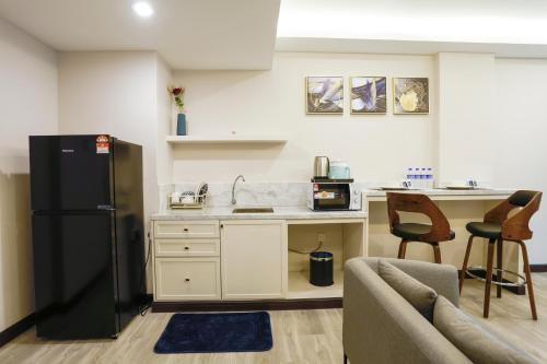 a kitchen with a black refrigerator and a couch at The Host Hotel in Ipoh