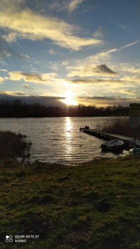 a sunset over a body of water with a dock at Domek całoroczny MARKO in Węgorzewo