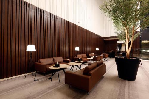 a lobby with couches and tables and a tree at ALMA Hotel Riyadh in Riyadh