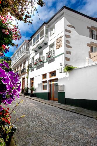 a white building with balconies on a street at SNÖ HOTEL CAMINO do EUME APARTAMENTOS in Puentedeume