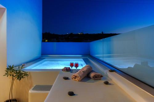 a bathtub with two glasses of wine and a towel at SantoRossa Luxury Villas in Emporio Santorini