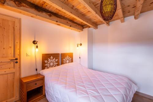 una camera da letto con un letto bianco e un soffitto in legno di Cal Bénétou - Belle Maison pour 12, vue montagne a Les Angles