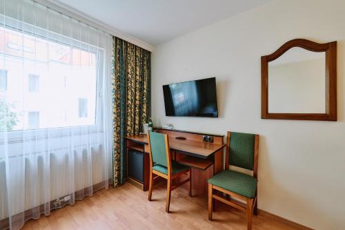 a room with a desk with two chairs and a mirror at Hotel Deutschmeister in Vienna