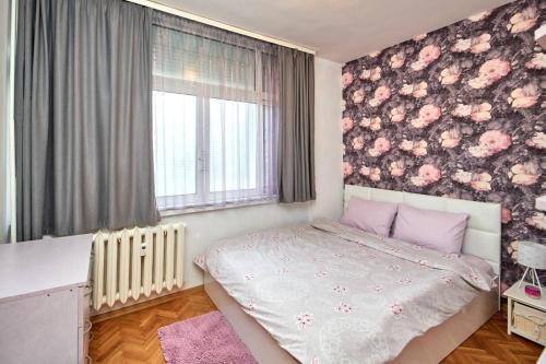 a bedroom with a bed with a floral wall at Апартамент Бриз in Burgas
