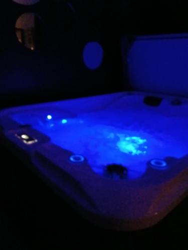 - une baignoire bleue dans une chambre sombre dans l'établissement Love Spa Normandie, à Saint-Pois