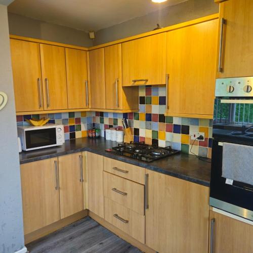 a kitchen with wooden cabinets and a stove top oven at Aldwych house, For Holidays, Contractors & Relocation, Free Parking & Wi-Fi in Preston