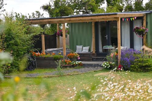 a green cabin with flowers in a garden at Sweet Pea Cabin in Badsey