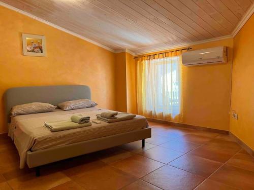 a bedroom with a bed with yellow walls and a window at Appartamento vista mare in Centro Storico in Scalea