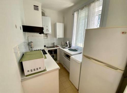 Il comprend une cuisine équipée d'appareils électroménagers blancs et d'un réfrigérateur blanc. dans l'établissement Les pieds dans le sable, au Grau-du-Roi