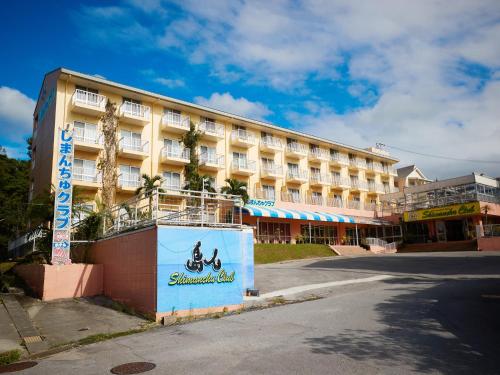 a hotel building with a sign in front of it at Condominium Hotel Shimanchu Club in Onna