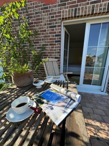 a picnic table with a book and a cup of coffee at Ferienwohnung Capitano in Eckwarden