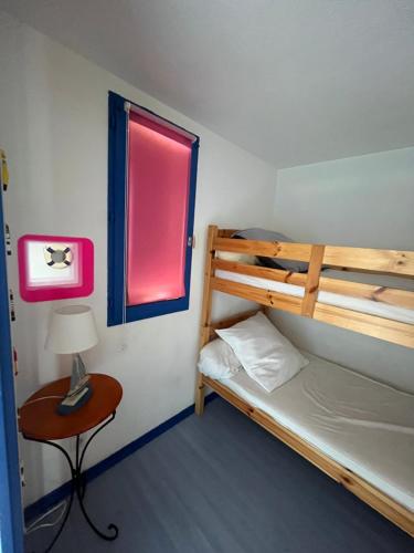 - une chambre avec des lits superposés, une table et une fenêtre dans l'établissement Location saisonnière Appartement 2 chambres à Palavas les flots, à Palavas-les-Flots