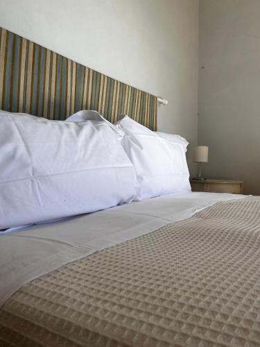 a bed with white sheets and pillows on it at The Monna Lisa Resort in Arezzo