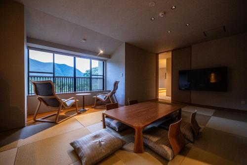 a living room with a table and chairs and a television at Oyado Ichizen in Yufuin
