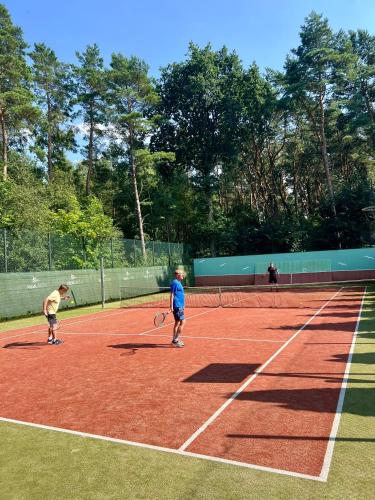 two children playing tennis on a tennis court at Alga Activ in Mrzeżyno