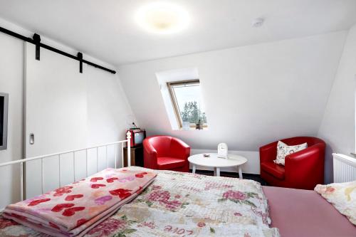 a bedroom with a bed and two red chairs at Wünsch Dir was in Großweitzschen