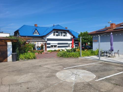 a white house with a blue roof in a parking lot at Willa Rudnik in Grudziądz