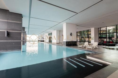 マラッカにあるThe Shore Premier Suites Melakaの白い椅子付きの建物内のスイミングプール