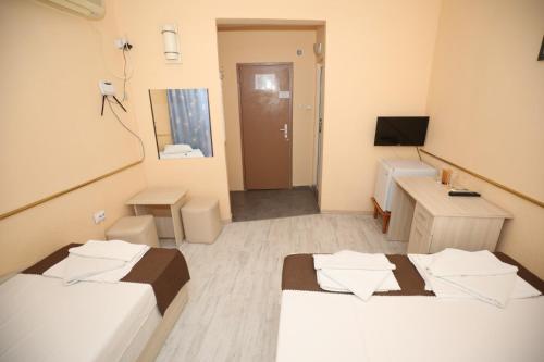a room with two beds and a desk and a television at Family Hotel White House in Pomorie