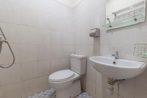 a bathroom with a toilet and a sink at Urbanview Hotel Sakura Bandung in Bandung