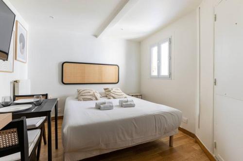 une chambre blanche avec un lit et un bureau dans l'établissement Montparnasse Rue de Rennes Charming apartment 2P, à Paris