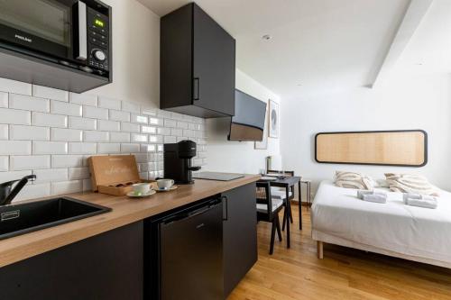 - une cuisine avec un comptoir et un lit dans une chambre dans l'établissement Montparnasse Rue de Rennes Charming apartment 2P, à Paris