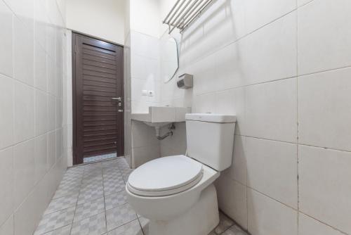 a white bathroom with a toilet and a sink at Urbanview Hotel Sakura Bandung in Bandung