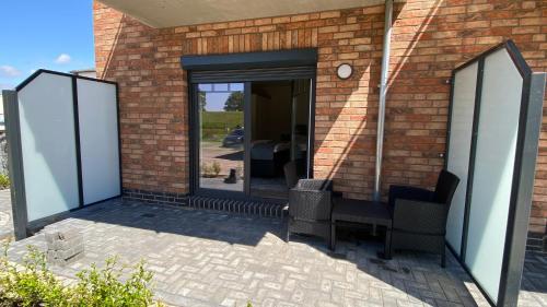 an open door of a brick building with two chairs at App2-SD9 Dieksand in Friedrichskoog