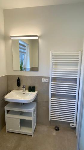 a bathroom with a white sink and a mirror at App3- SD26 Paloma-G in Friedrichskoog