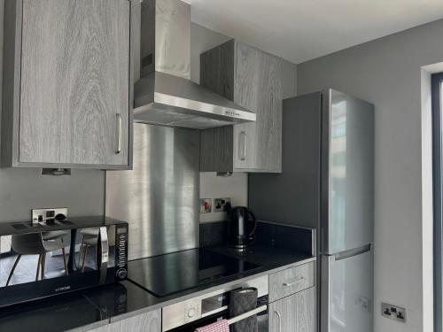 a kitchen with a black counter top and stainless steel appliances at Monarchs Quay Arena Apartments by Happy Days in Liverpool