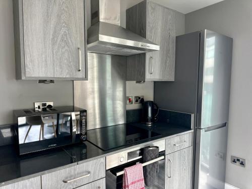 a kitchen with a microwave and a black counter top at Monarchs Quay Arena Apartments by Happy Days in Liverpool