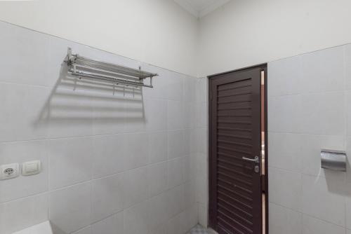a bathroom with a brown door and white tiles at Urbanview Hotel Sakura Bandung in Bandung