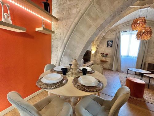 d'une salle à manger avec une table, des chaises et un mur orange. dans l'établissement Joli appartement voûté dans le centre ville, à Avignon
