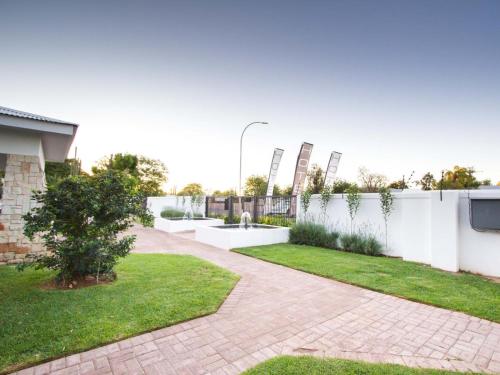 a backyard with a white fence and a garden at Maxton Boutique Hotel Upington in Upington