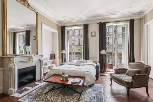 - une chambre avec un lit, une cheminée et une chaise dans l'établissement Elégant appartement parisien, à Paris