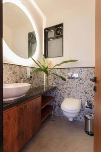 a bathroom with a sink and a toilet and a mirror at Nistula Luxury Villa with Private Pool in Assagao in Assagao