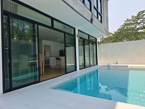 a house with a swimming pool with glass windows at Joy Homes Private Pool Villa in Chiang Mai