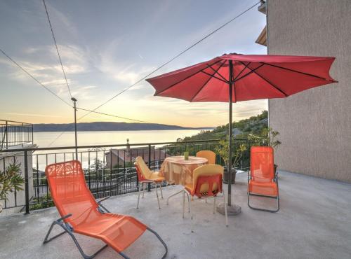 un patio avec une table, des chaises et un parasol dans l'établissement Apartments Luka & Leona, à Senj