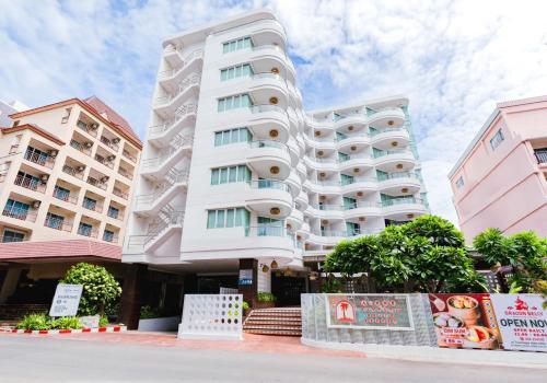 a tall white building in front of two pink buildings at A-ONE Pattaya Beach Resort in Pattaya