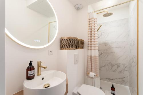 une salle de bain blanche avec un lavabo et un miroir dans l'établissement Ty Peskaiden 1 - à Cancale vue mer, à Cancale
