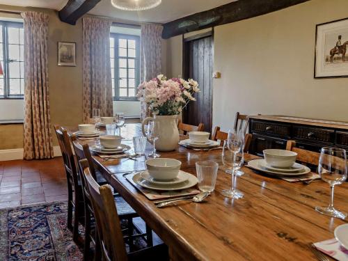 a dining room with a wooden table with chairs and flowers at Elizabethan Manor at gateway to the Brecon Beacons in Abergavenny