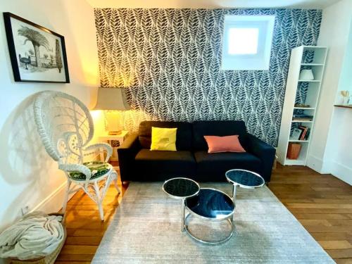 - un salon avec un canapé noir et des chaises dans l'établissement Beau 2P au pied de Montmartre, à Paris