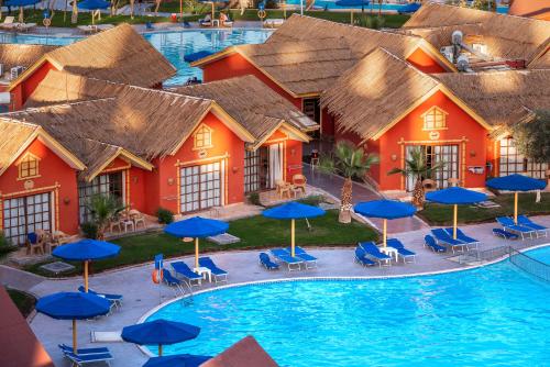 an aerial view of a resort with a pool and blue umbrellas at Pickalbatros Jungle Aqua Park - Neverland Hurghada in Hurghada