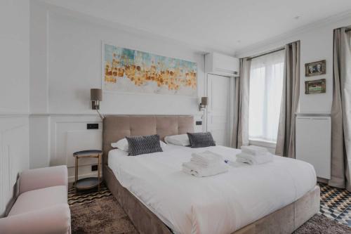une chambre avec un grand lit blanc et une chaise dans l'établissement Charming apartment - 1BR-4P - Arc de triomphe, à Paris