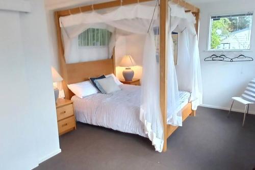 a bedroom with a large bed with a canopy at The Harbour Masters Cottage in Tairua