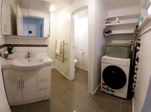 ein Badezimmer mit Waschbecken und Waschmaschine in der Unterkunft The Harbour Masters Cottage in Tairua