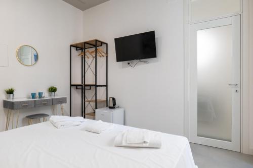 a white room with a bed and a tv on the wall at Relais Palazzo Nizza - Luxotel & Apartotel in Salerno