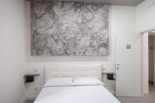 a bedroom with a white bed and a painting on the wall at Relais Palazzo Nizza - Luxotel & Apartotel in Salerno